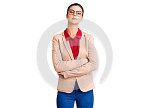 Young beautiful woman wearing business shirt and glasses relaxed with serious expression on face