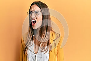 Young beautiful woman wearing business style and glasses angry and mad screaming frustrated and furious, shouting with anger