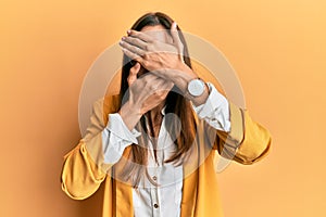 Young beautiful woman wearing business style and glasses covering eyes and mouth with hands, surprised and shocked