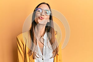 Young beautiful woman wearing business style and glasses looking at the camera blowing a kiss on air being lovely and sexy