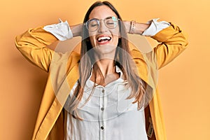 Young beautiful woman wearing business style and glasses relaxing and stretching, arms and hands behind head and neck smiling