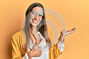 Young beautiful woman wearing business style and glasses showing palm hand and doing ok gesture with thumbs up, smiling happy and