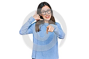 Young beautiful woman wearing casual clothes and glasses smiling doing talking on the telephone gesture and pointing to you