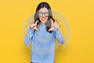 Young beautiful woman wearing casual clothes and glasses smiling funny doing claw gesture as cat, aggressive and sexy expression