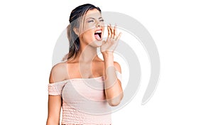 Young beautiful woman wearing casual clothes shouting and screaming loud to side with hand on mouth