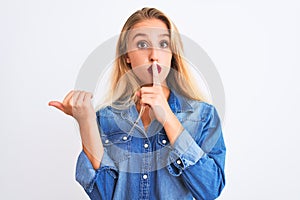 Young beautiful woman wearing casual denim shirt standing over isolated white background asking to be quiet with finger on lips
