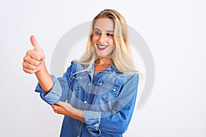 Young beautiful woman wearing casual denim shirt standing over isolated white background Looking proud, smiling doing thumbs up