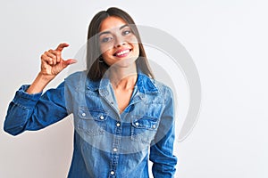 Young beautiful woman wearing casual denim shirt standing over isolated white background smiling and confident gesturing with hand