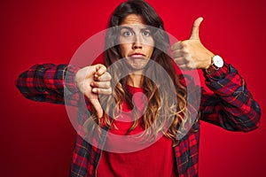 Young beautiful woman wearing casual jacket standing over red isolated background asking to be quiet with finger on lips