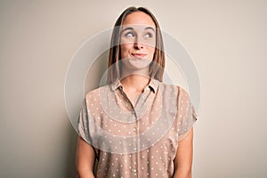 Young beautiful woman wearing casual shirt standing over isolated white background smiling looking to the side and staring away