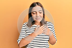 Young beautiful woman wearing casual striped t shirt smiling with hands on chest, eyes closed with grateful gesture on face