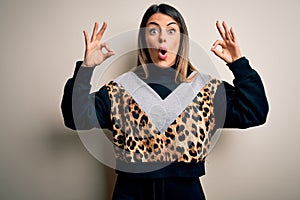 Young beautiful woman wearing casual sweatshirt standing over isolated white background looking surprised and shocked doing ok