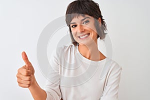 Young beautiful woman wearing casual t-shirt standing over isolated white background happy with big smile doing ok sign, thumb up