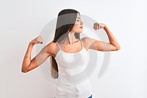 Young beautiful woman wearing casual t-shirt standing over isolated white background showing arms muscles smiling proud
