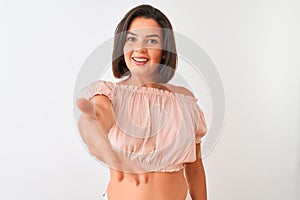 Young beautiful woman wearing casual t-shirt standing over isolated white background smiling friendly offering handshake as