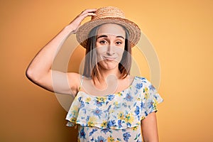 Young beautiful woman wearing casual t-shirt and summer hat over isolated yellow background confuse and wonder about question