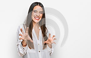 Young beautiful woman wearing casual white shirt smiling funny doing claw gesture as cat, aggressive and sexy expression