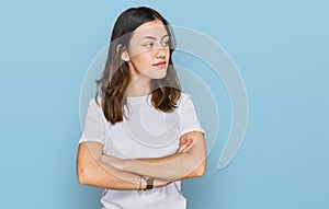 Young beautiful woman wearing casual white t shirt looking to the side with arms crossed convinced and confident