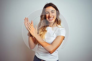 Young beautiful woman wearing casual white t-shirt over isolated background clapping and applauding happy and joyful, smiling