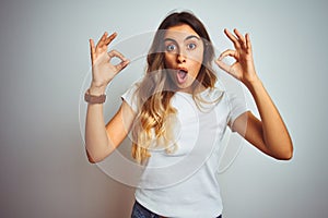 Young beautiful woman wearing casual white t-shirt over isolated background looking surprised and shocked doing ok approval symbol