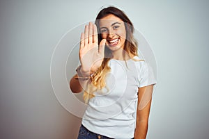 Young beautiful woman wearing casual white t-shirt over isolated background Waiving saying hello happy and smiling, friendly