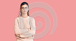 Young beautiful woman wearing casual winter sweater and glasses skeptic and nervous, disapproving expression on face with crossed photo