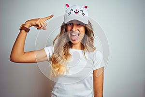 Young beautiful woman wearing cat cap over grey isolated background very happy pointing with hand and finger