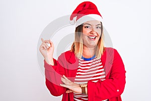 Young beautiful woman wearing Christmas Santa hat over isolated white background with a big smile on face, pointing with hand and