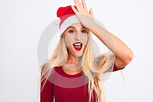 Young beautiful woman wearing Christmas Santa hat over isolated white background surprised with hand on head for mistake, remember