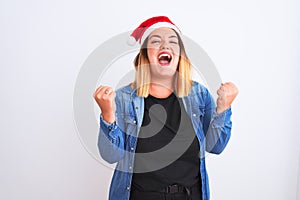 Young beautiful woman wearing Christmas Santa hat standing over isolated white background celebrating surprised and amazed for