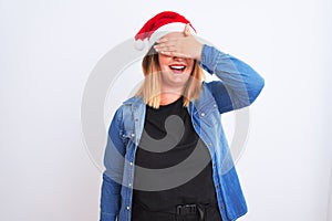 Young beautiful woman wearing Christmas Santa hat standing over isolated white background smiling and laughing with hand on face