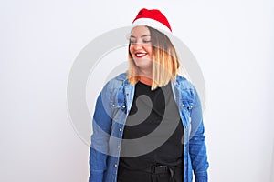 Young beautiful woman wearing Christmas Santa hat standing over  white background looking away to side with smile on face,