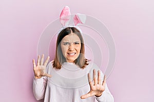 Young beautiful woman wearing cute easter bunny ears afraid and terrified with fear expression stop gesture with hands, shouting
