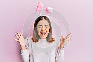 Young beautiful woman wearing cute easter bunny ears celebrating mad and crazy for success with arms raised and closed eyes