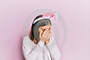 Young beautiful woman wearing cute easter bunny ears with sad expression covering face with hands while crying