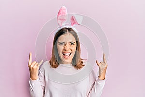 Young beautiful woman wearing cute easter bunny ears shouting with crazy expression doing rock symbol with hands up