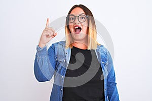 Young beautiful woman wearing denim shirt and glasses over isolated white background pointing finger up with successful idea