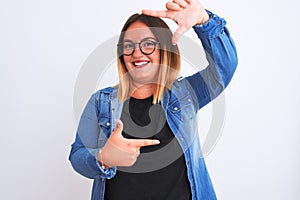Young beautiful woman wearing denim shirt and glasses over isolated white background smiling making frame with hands and fingers
