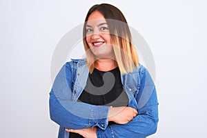 Young beautiful woman wearing denim shirt standing over isolated white background happy face smiling with crossed arms looking at