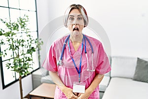 Young beautiful woman wearing doctor uniform and stethoscope sticking tongue out happy with funny expression