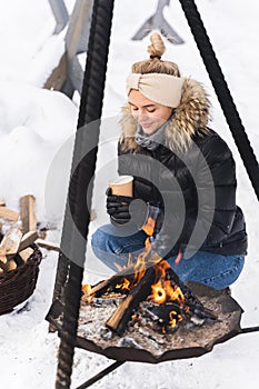 Beautiful woman warming up by the fire pit during cold winter day