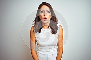Young beautiful woman wearing dress standing over white isolated background afraid and shocked with surprise and amazed