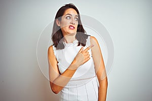 Young beautiful woman wearing dress standing over white isolated background Pointing aside worried and nervous with forefinger,