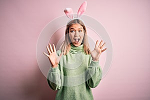 Young beautiful woman wearing easter rabbit ears standing over isolated pink background celebrating crazy and amazed for success