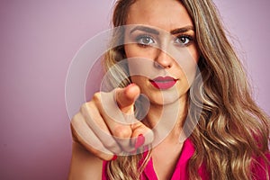 Young beautiful woman wearing elegant shirt standing over pink isolated background pointing with finger to the camera and to you,