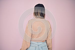 Young beautiful woman wearing fashionable clothes standing backwards over isolated pink background