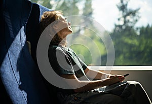 Young beautiful woman wearing glasses sitting in a chair in a high-speed train relaxing while traveling