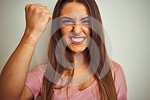 Young beautiful woman wearing pink t-shirt standing over isolated white background annoyed and frustrated shouting with anger,