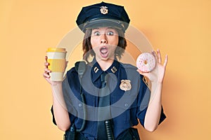 Young beautiful woman wearing police uniform holding donut and take away coffee afraid and shocked with surprise and amazed