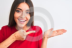 Young beautiful woman wearing red casual t-shirt standing over isolated white background very happy pointing with hand and finger